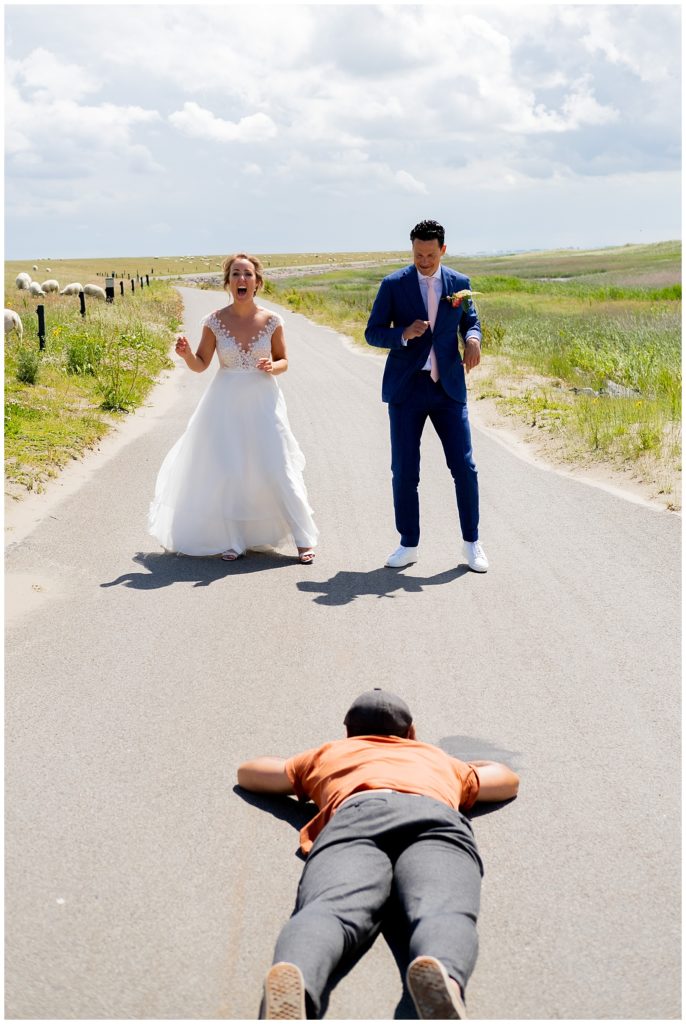 trouwfotograaf ligt op het asflat om bruidspaar te fotograferen