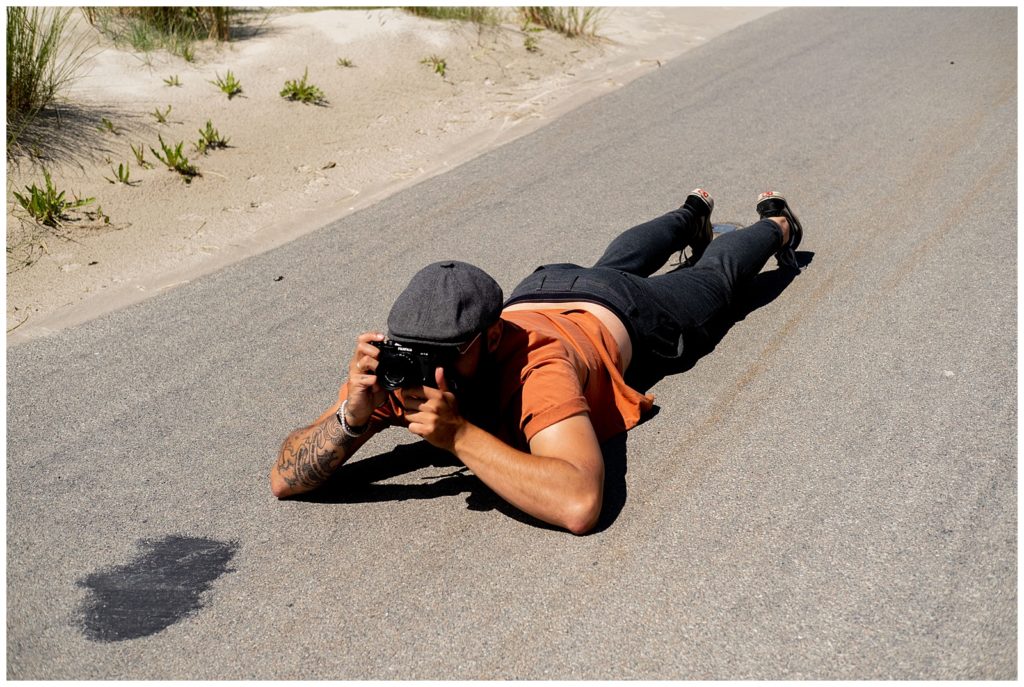 trouwfotograaf maakt foto van bruidspaar liggen op asfalt